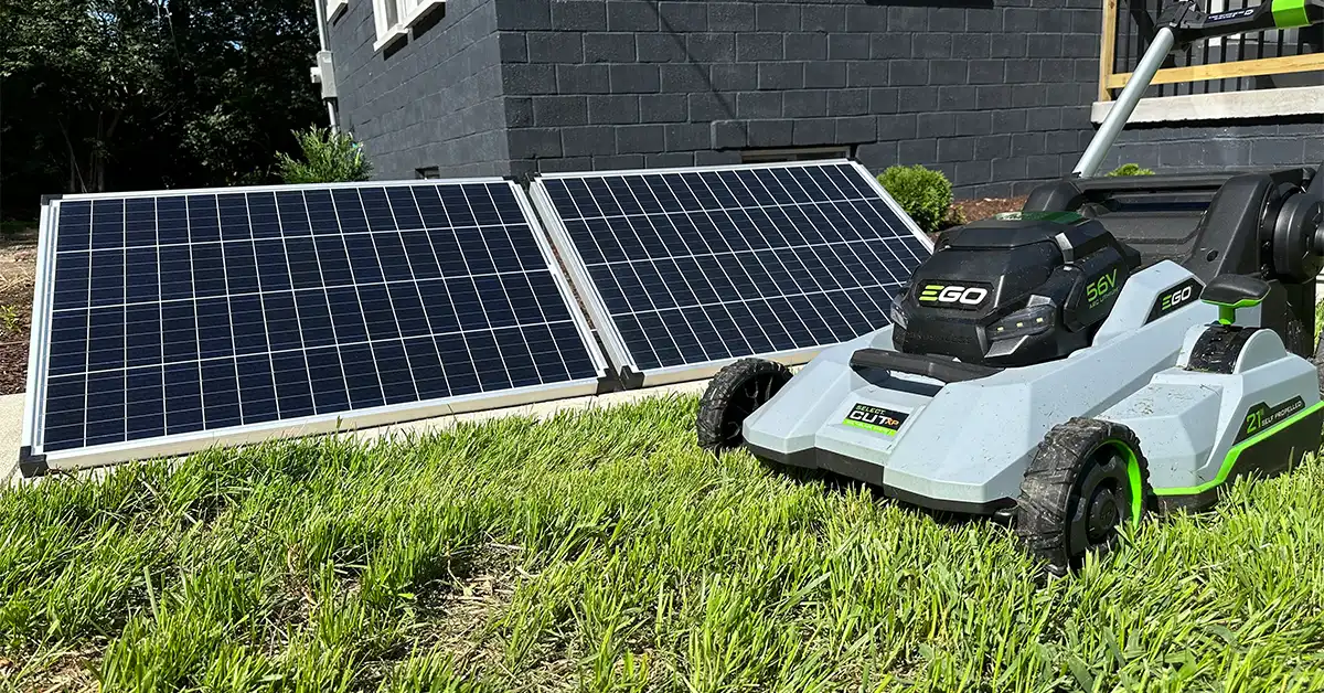 An image of an EGO Lawnmower with two solar panels in the background.