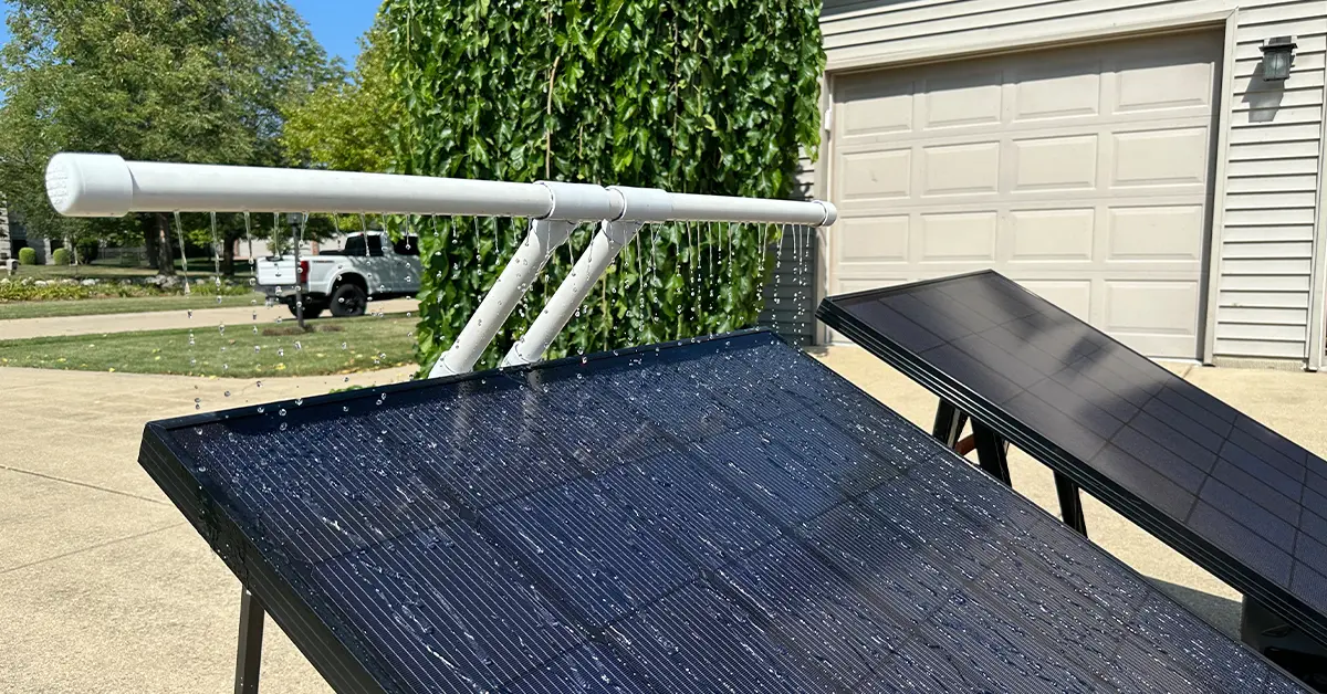 An image showing a sprayer bar spraying water onto a 360-watt solar panel.